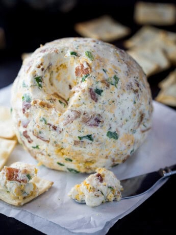 A bacon ranch cheese ball on surrounded by crackers.