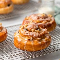 Homemade Cinnamon Rolls on a cooling rack with icing on top.