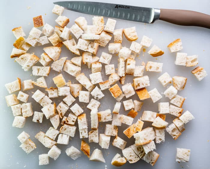 bread on a cutting board cut into cubes for homemade croutons.