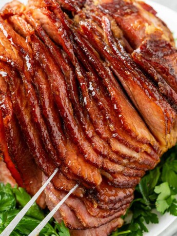 A platter topped with glazed ham on top of parsley.