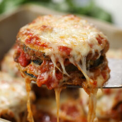 Zucchini Parmesan being held up with a spatula.