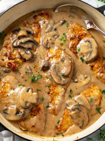 Mushroom Chicken in a skillet with sauce, mushrooms, and thyme.