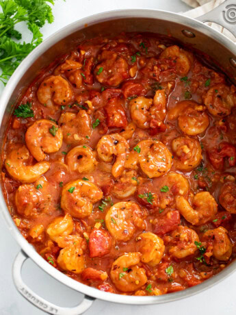 A skillet of Shrimp Fra Diavolo with a spicy tomato sauce and parsley on the side.