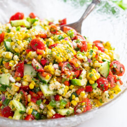 Corn Salad in a glass bowl with vegetables, cilantro, and dressing.