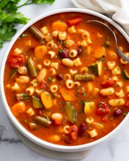 Minestrone Soup in a white bowl with a spoon on the side.