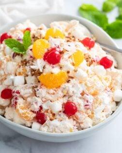 Creamy Ambrosia Salad in a white bowl with cherries and mandarin oranges on top.