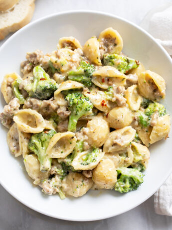 A white bowl with Sausage and Broccoli Pasta in a creamy sauce.