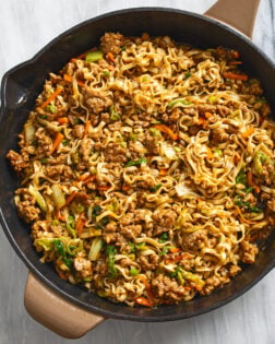 Pork Noodles in a cast iron skillet with julienne carrots, cabbage, ground pork, egg noodles, and sauce.