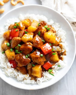 Pineapple Chicken over rice in a white bowl with a glossy sauce.