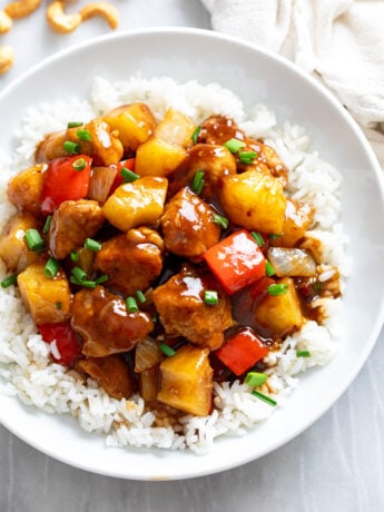 Pineapple Chicken over rice in a white bowl with a glossy sauce.