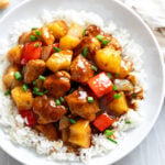 A white bowl filled with Pineapple Chicken over white rice.