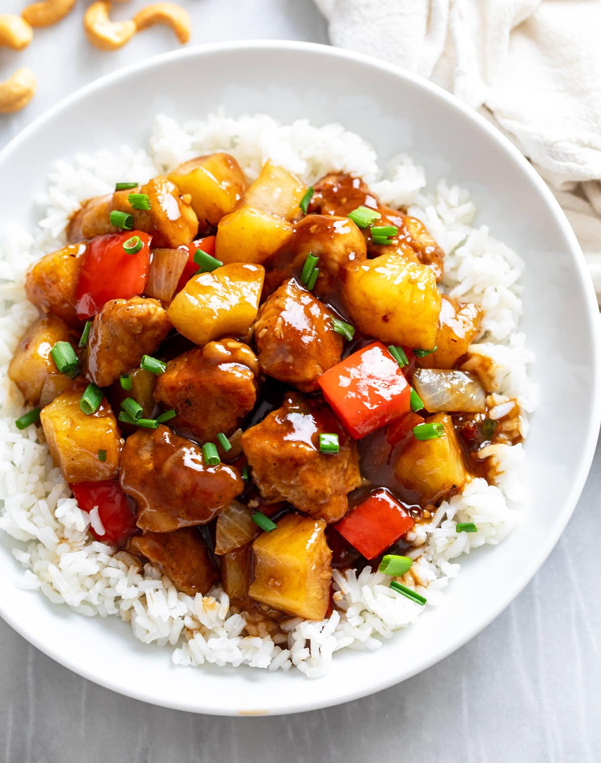 Pineapple Chicken over rice in a white bowl with a glossy sauce.