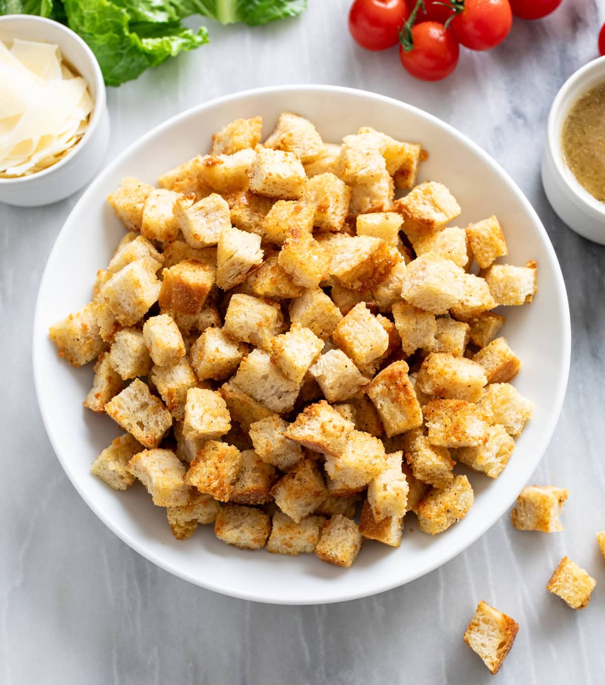 Homemade Croutons in a white bowl on a white marble surface.
