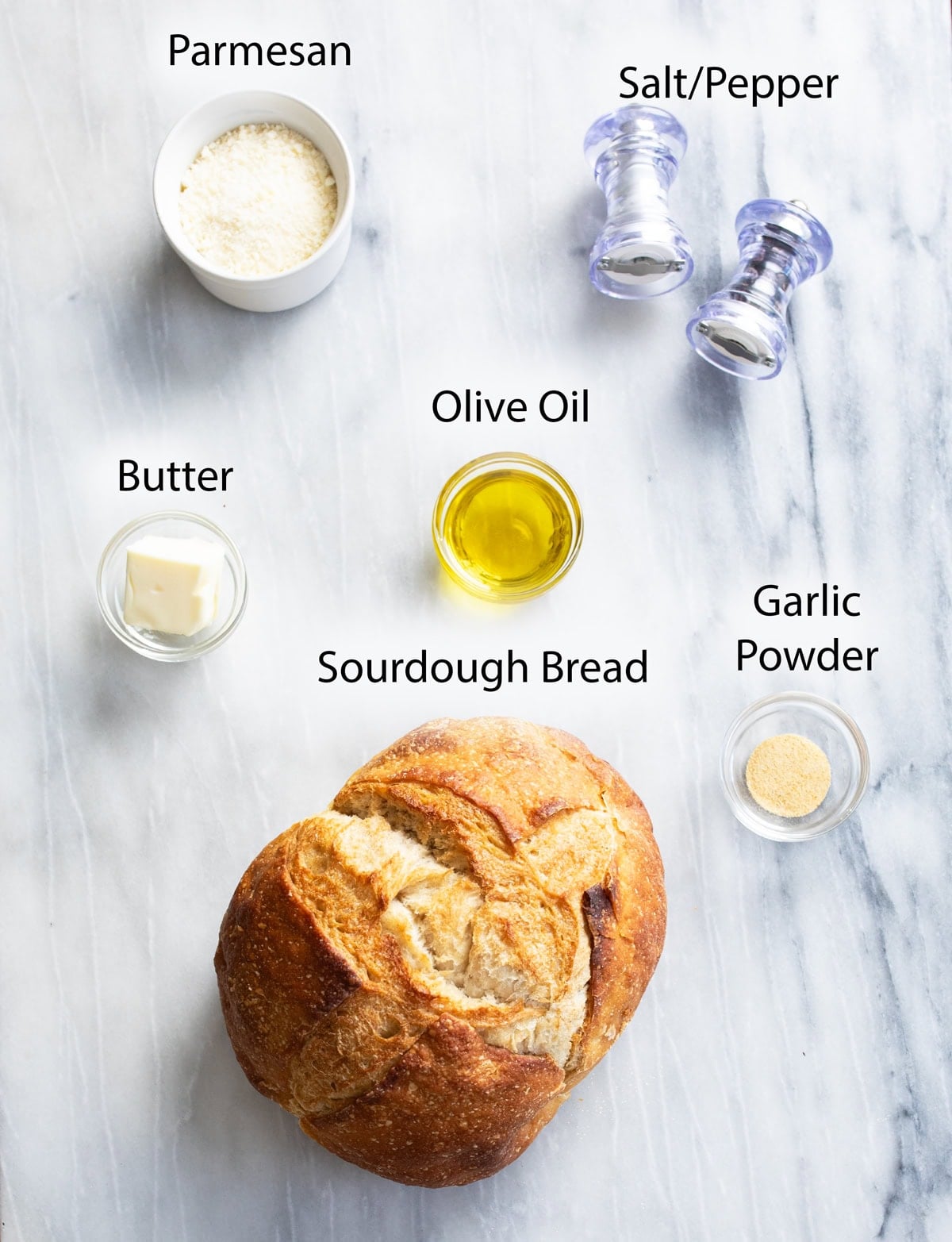 Overhead view of ingredients on a white surface that are needed to make homemade croutons.