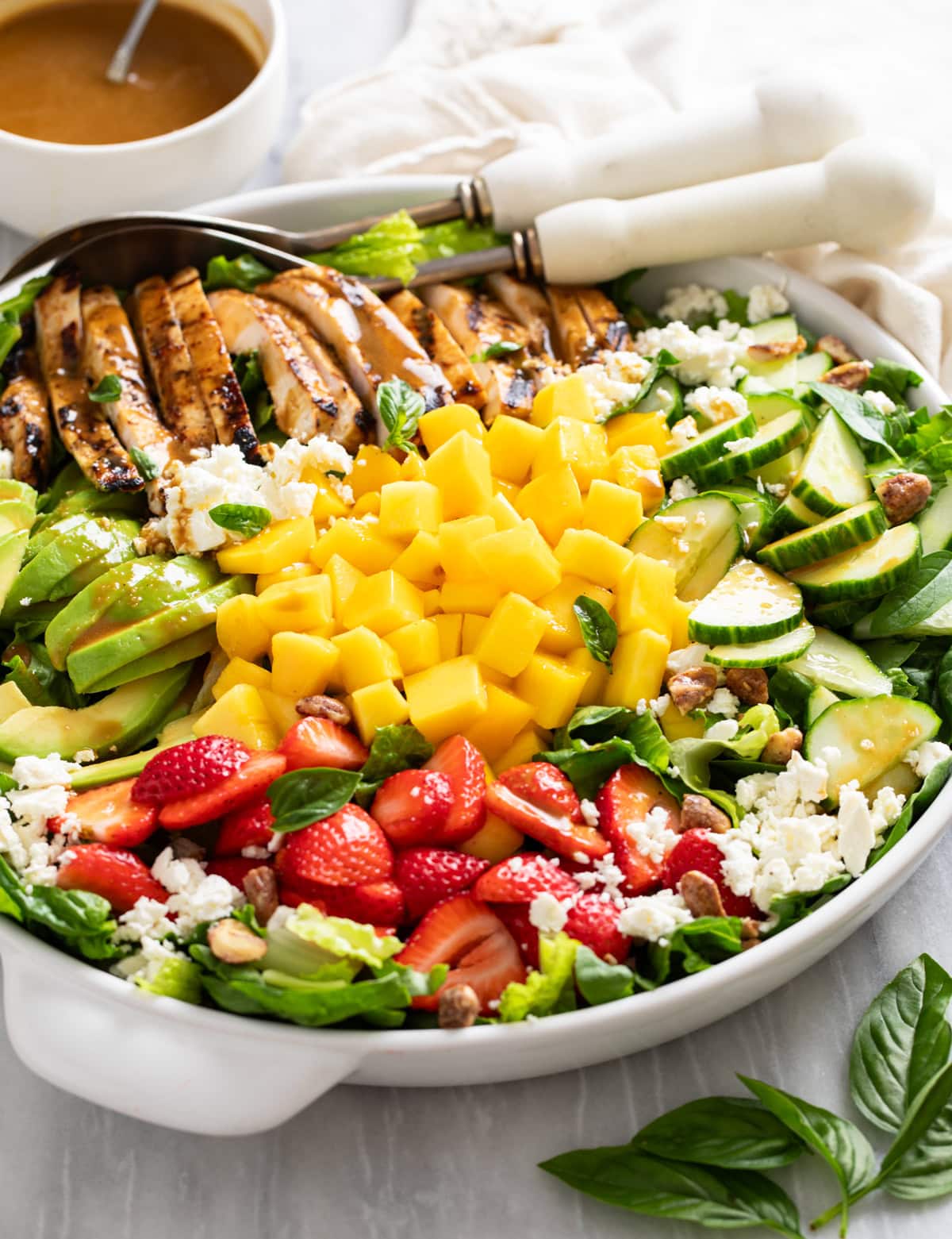 Side view of mango salad in a white serving platter with mango in the middle and fruit and veggies around the outside.
