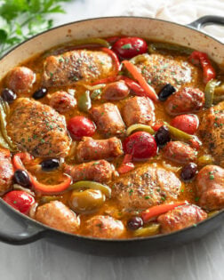 Chicken Scarpariello in a skillet with cherry peppers, bell peppers, and sauce.