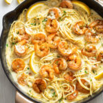 Lemon Shrimp Pasta in a skillet with a creamy lemon sauce topped with fresh parsley and slices of fresh lemon.